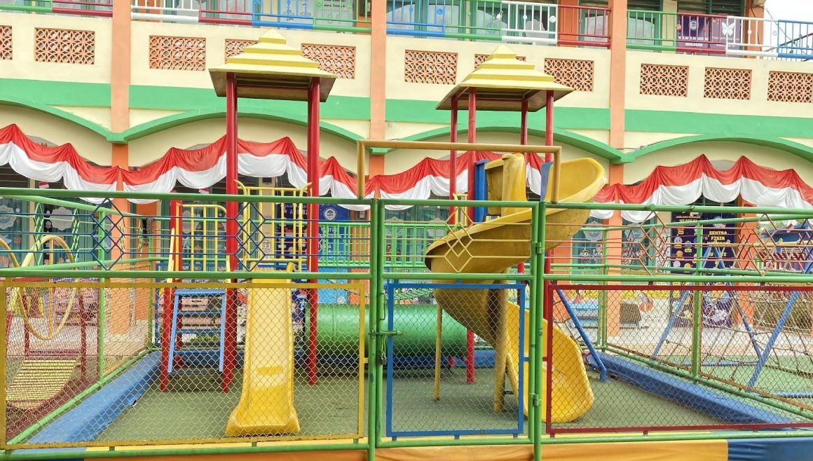 Taman bermain berpagar dengan menara panjat dan perosotan kuning