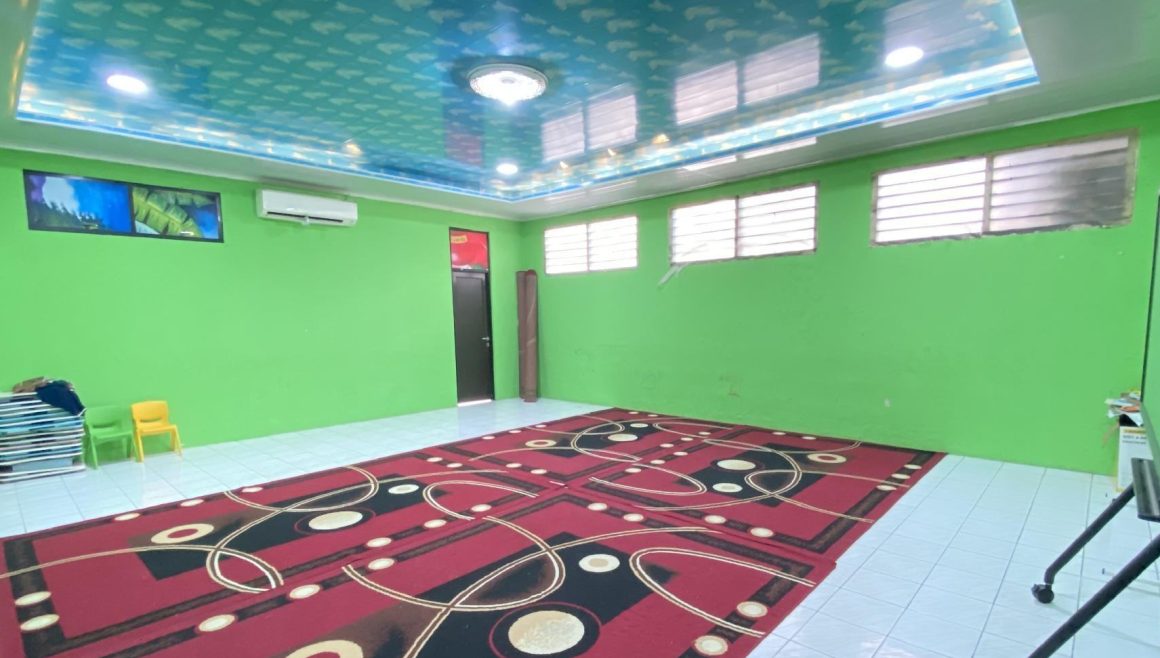 Ruangan luas berdinding hijau dengan karpet merah bermotif