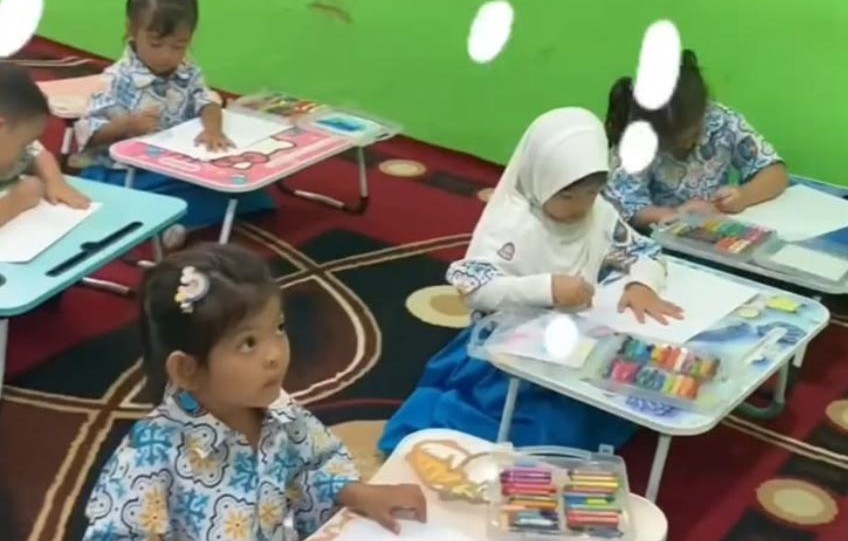 Anak-anak mewarnai gambar dengan krayon di meja lipat kelas